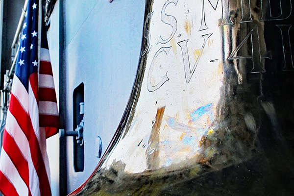 Bell of the USS Midway and United States flag at the entrance of the USS Midway Museum.